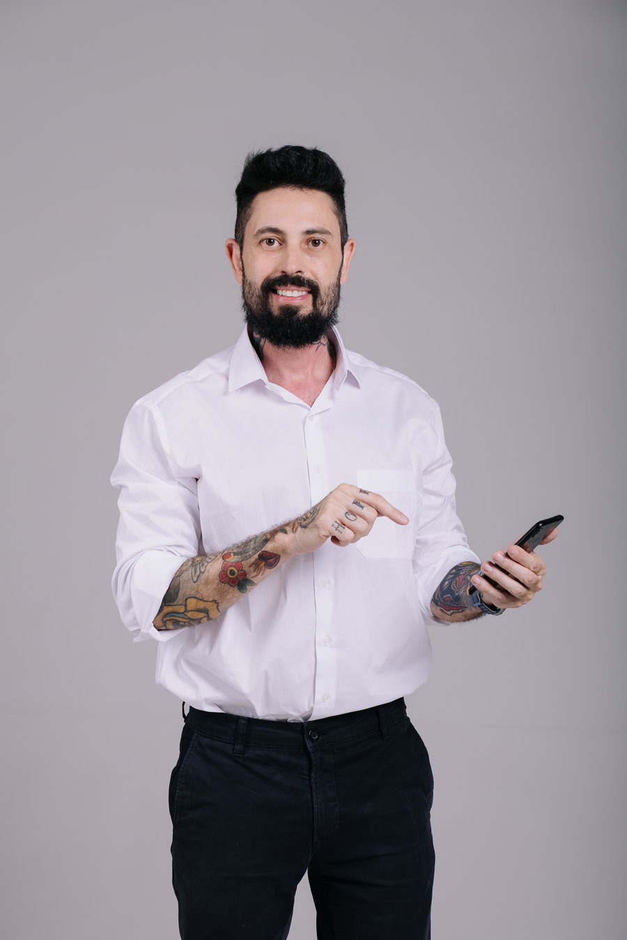 Delegado Yasser sorrindo, de camisa branca com as mangas dobradas, segurando o celular e apontando para a tela