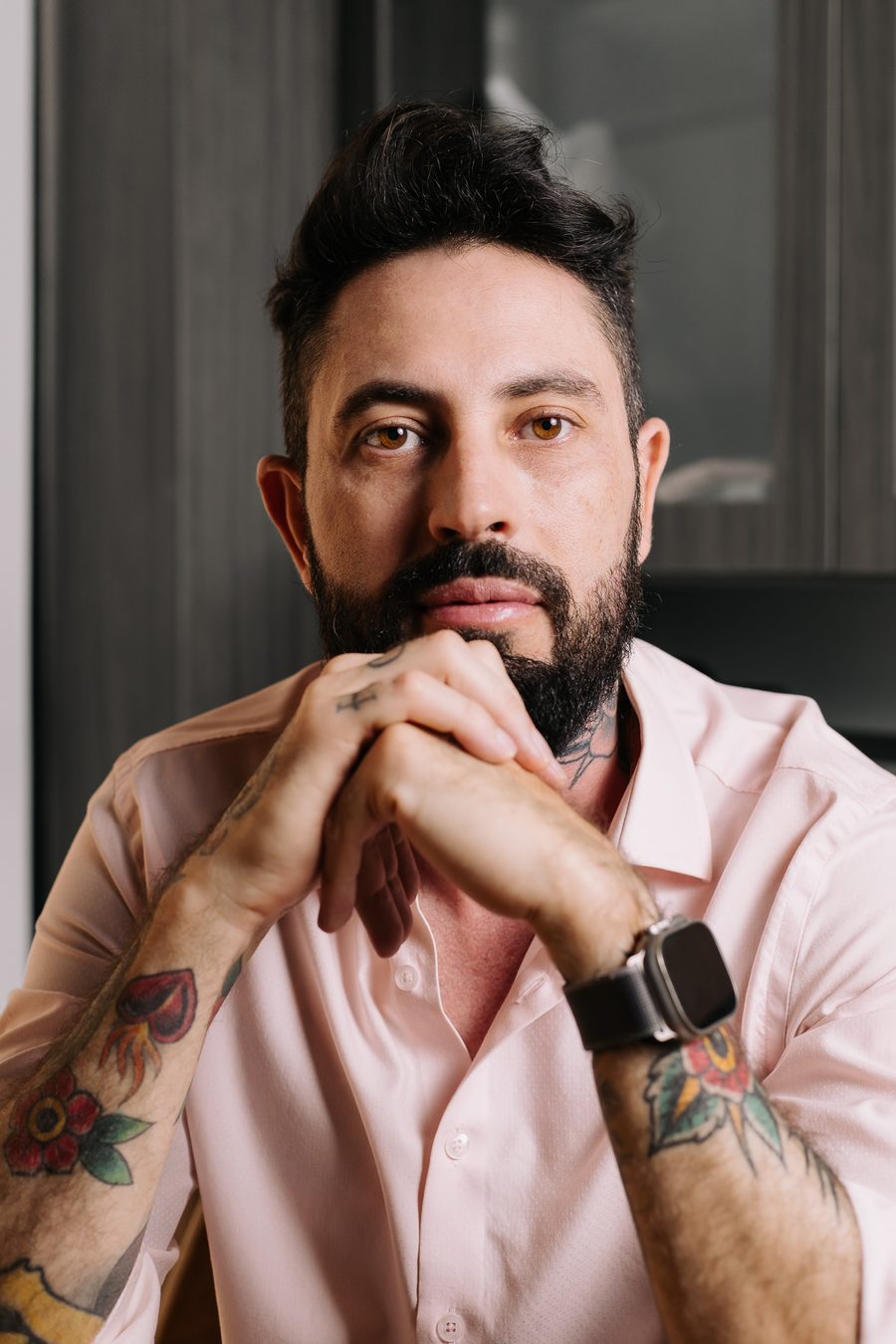 Retrato pensativo do Delegado Yasser, de camisa rosa-claro, com o queixo apoiado nas mãos unidas